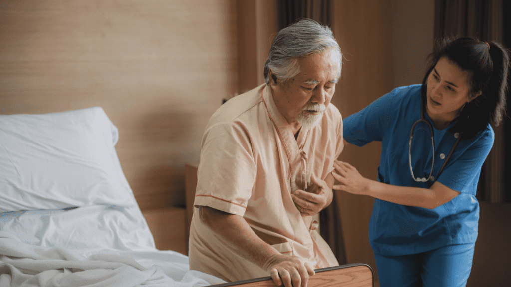 senior man holding his chest while being assisted by a caregiver