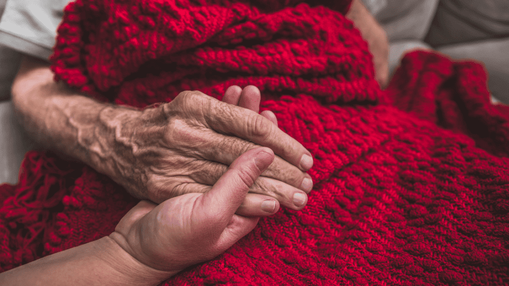 a care giver holding a hand of an elderly