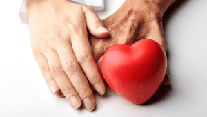 hands of a senior and adult with a red heart shape