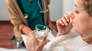 a caregiving giving medicine to a senior lady